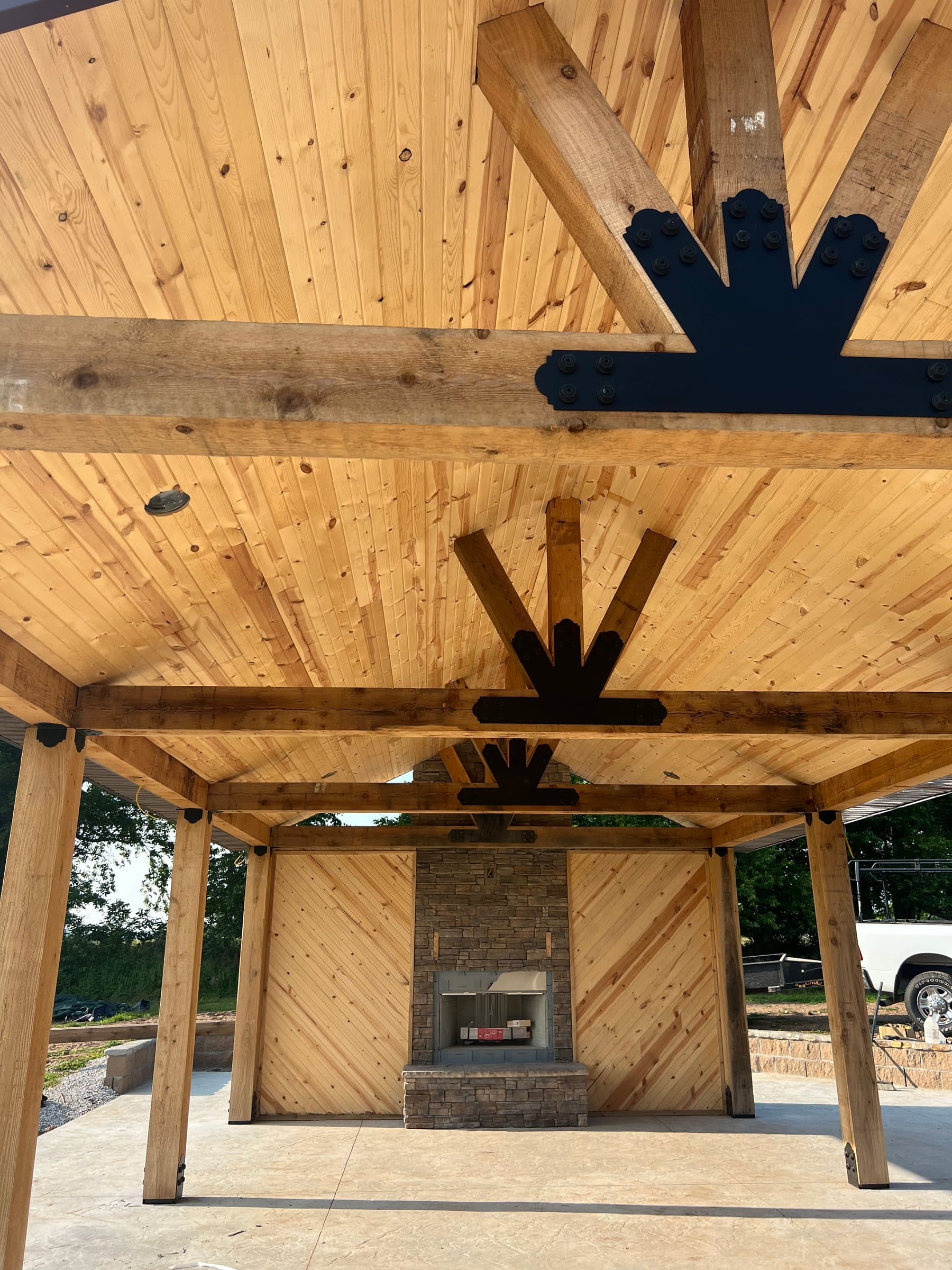 A cedar pavilion ceiling with black steel sunburst brackets above a stone fireplace.