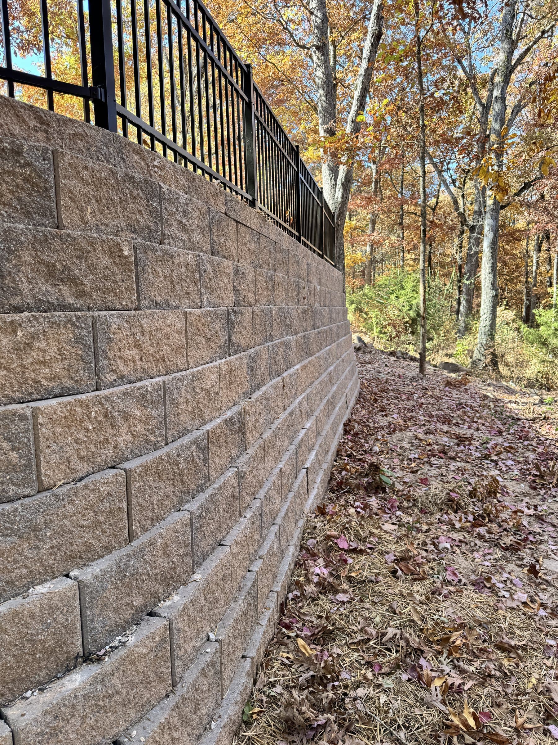 Segmental block retaining wall with a fence above