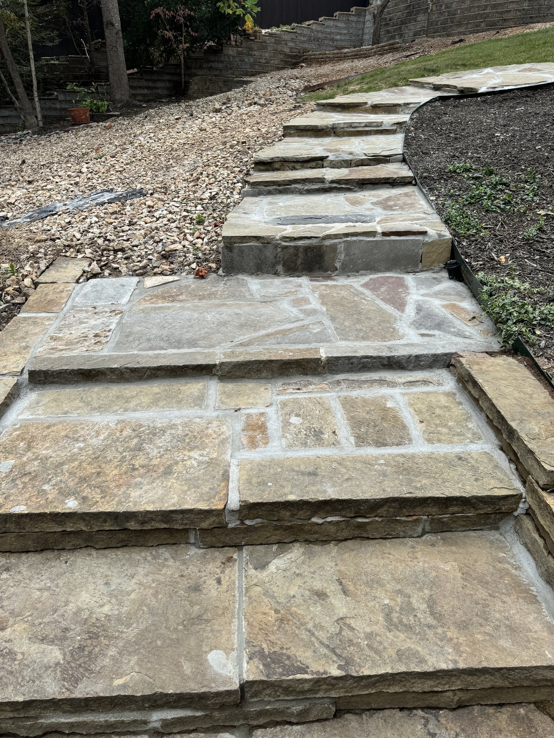 Natural flagstone steps climbing a gravel slope between planting beds.