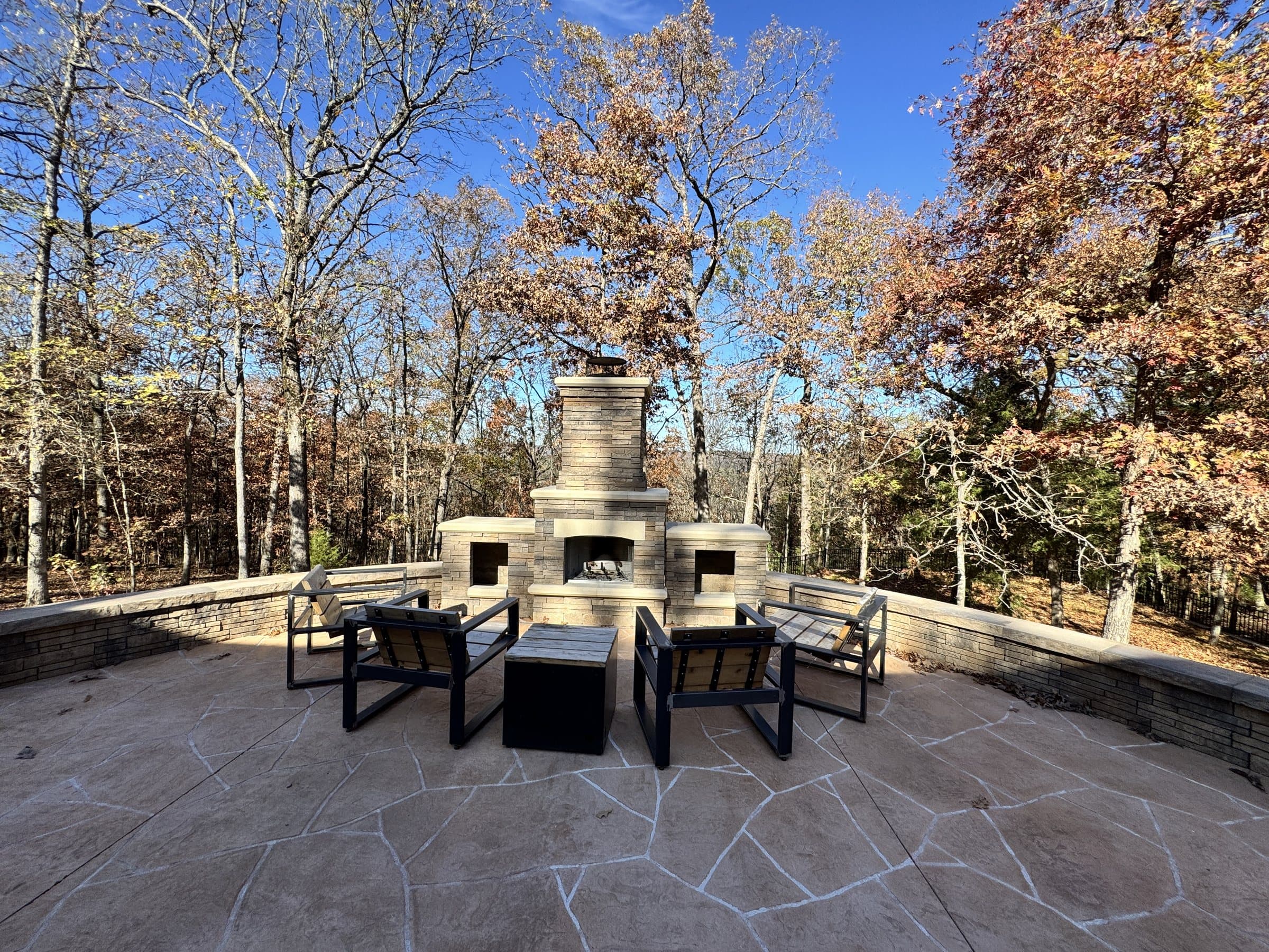 Stone fireplace, seating wall and patio on a wooded Ozark lot